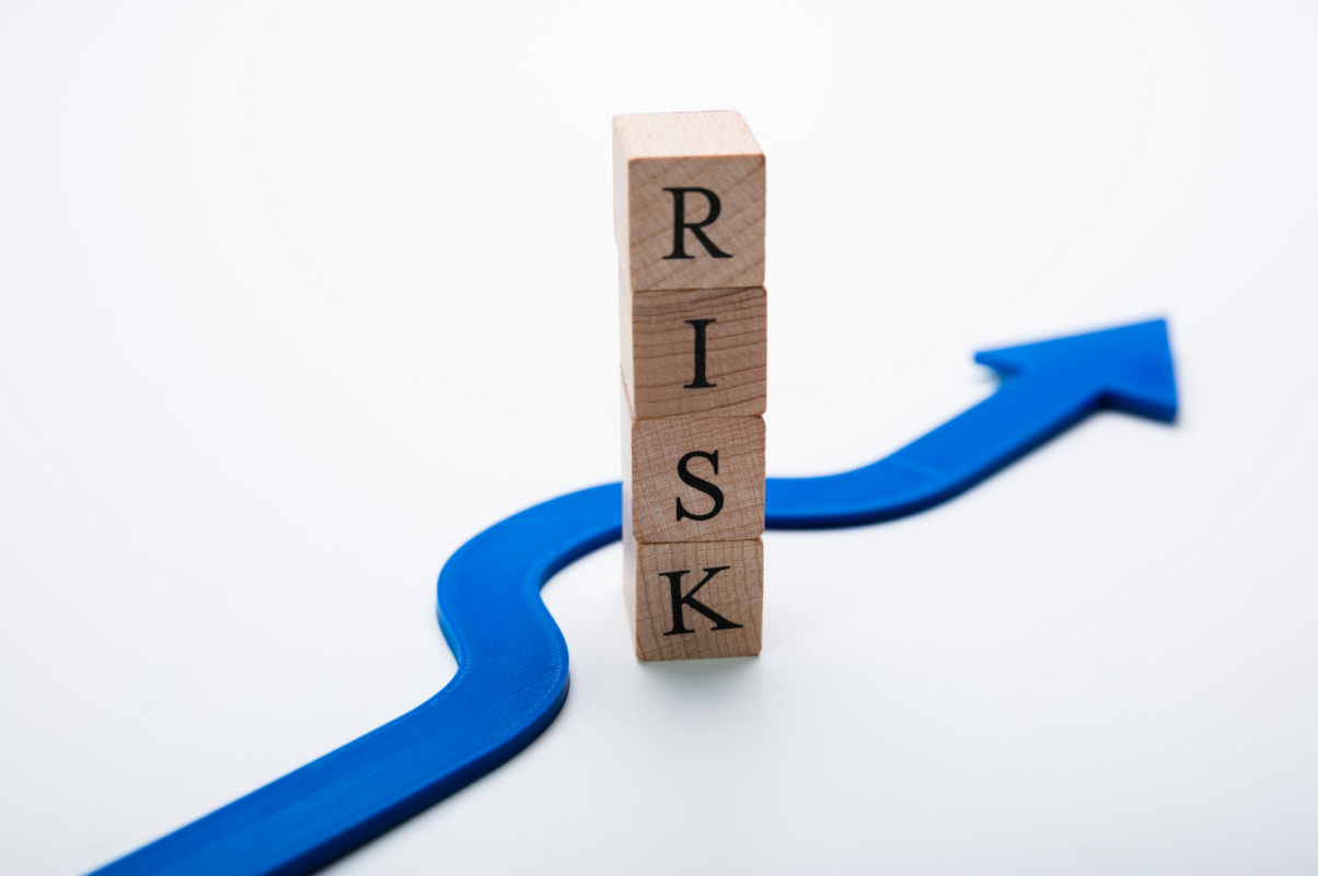 Holzklötze formen das Wort Risk, Blauer Pfeil im Hintergrund