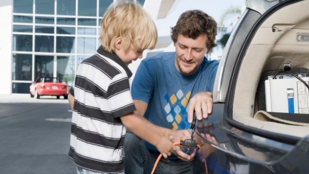Vater und Sohn stecken ein Elektroauto an.